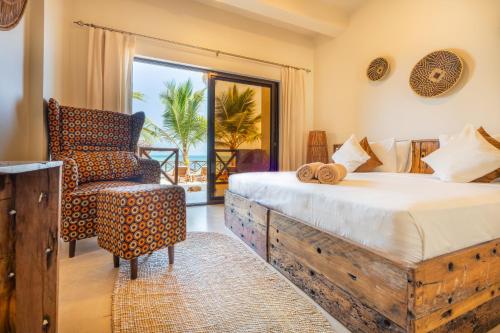a bedroom with a bed and a chair and a window at Tangawizi Lodge Zanzibar - Adults Only in Jambiani