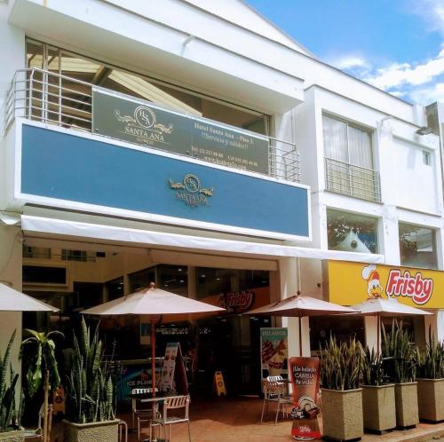 a building with tables and umbrellas in front of it at Suite de hotel dentro centro comercial in Cartago