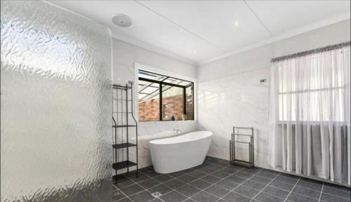 a white bathroom with a tub and a window at The Haven House in Singleton