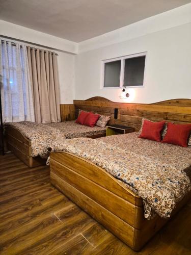 a bedroom with two beds with red pillows at Ratnagiri Boutique Hotel in Mirik