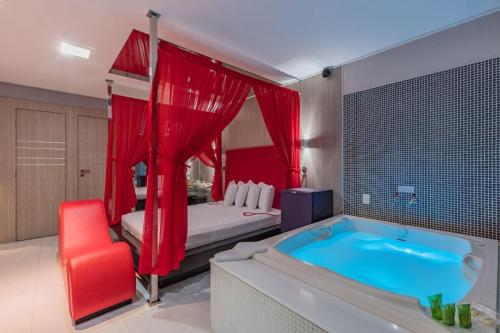 a bathroom with a tub and a bed with red curtains at Spa urbano Motel Adult Only in Fortaleza