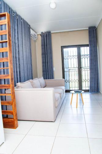 a living room with a white couch and blue curtains at The River Boutique Inn in Lobamba