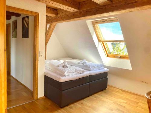 a small bed in a room with a window at Gemütliche Landhauswohnung in Bad Saulgau