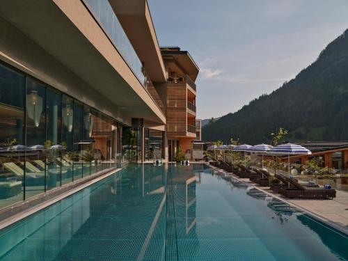a hotel with a swimming pool with mountains in the background at DAS EDELWEISS - Salzburg Mountain Resort in Grossarl