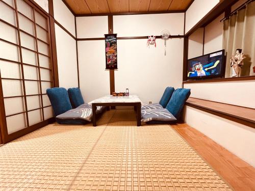 a room with chairs and a table and a tv at 梅小路民宿 in Kyoto