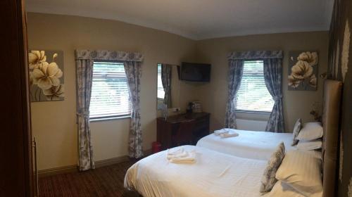 a bedroom with two beds and two windows at The Griffin Inn in Saint Helens