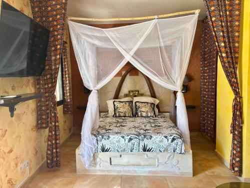 a bedroom with a canopy bed and a tv at Téranga paradis in Somone