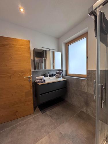 a bathroom with a sink and a window and a shower at Ferienwohnungen Moser in Steinberg am Rofan