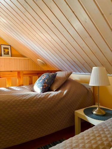 a bed in a room with a wooden ceiling at Linkkumylly Cottages in Mäntyharju
