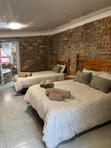 a bedroom with three beds and a brick wall at 14 Mirage crescent in Welkom