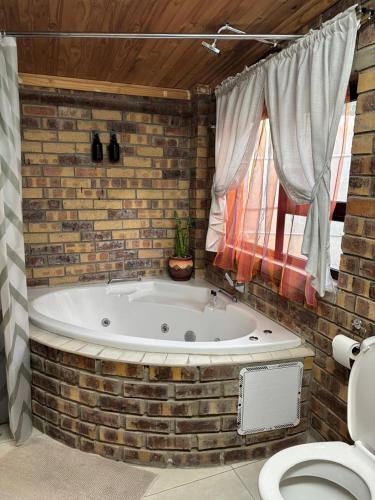 a bath tub in a brick walled bathroom with a toilet at 14 Mirage crescent in Welkom