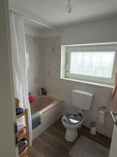 a bathroom with a toilet and a tub and a window at Quendel & Äpfel Ferienhaus in Neu Wulmstorf