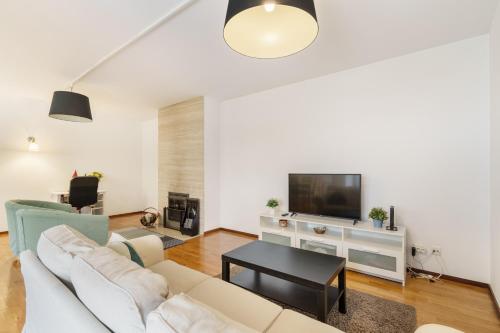 a living room with a white couch and a tv at Lodge confortável na Sé - Minho's Guest in Braga