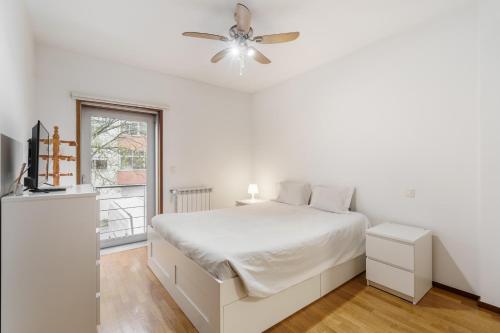 a white bedroom with a bed and a ceiling fan at Lodge confortável na Sé - Minho's Guest in Braga