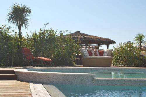 a swimming pool with chairs and a gazebo at Le Sable Fin Beach House in Viareggio