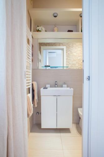 a bathroom with a white sink and a mirror at Le Sable Fin Beach House in Viareggio