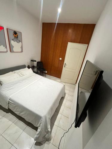 Un dormitorio con una cama y un televisor. en Chambre Standard, en Dakar
