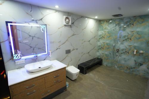 a bathroom with a sink and a shower with a mirror at Hotel Konaaz Inn in Alīgarh