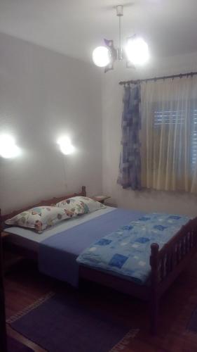 a bedroom with a bed with blue sheets and a window at Guesthouse Filepi in Senj