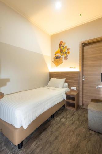 a bedroom with a bed and a painting on the wall at Front One Budget Malioboro Jogja in Yogyakarta