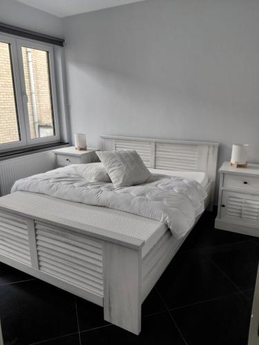 a white bed in a room with two windows at App ZeeVorm Nieuw in De Panne