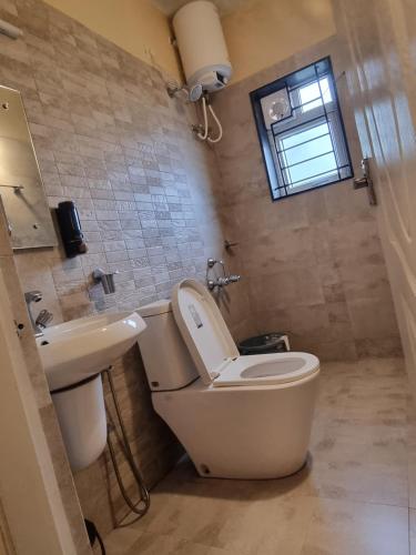 a bathroom with a toilet and a sink at Honey Bee Cottages in Ooty