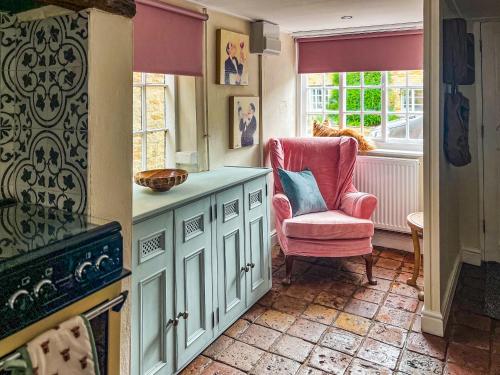 a kitchen with a pink chair and a window at Teddy's Cottage in Market Overton