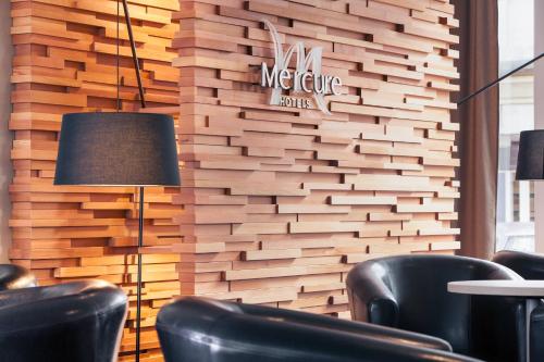 a meeting room with black chairs and a wooden wall at Hôtel Mercure Marne-la-Vallée Bussy St Georges in Bussy-Saint-Georges