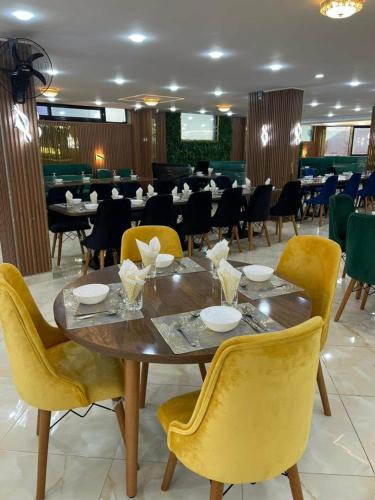 a dining room with a wooden table and yellow chairs at Appart hôtel palais de mer in Jijel