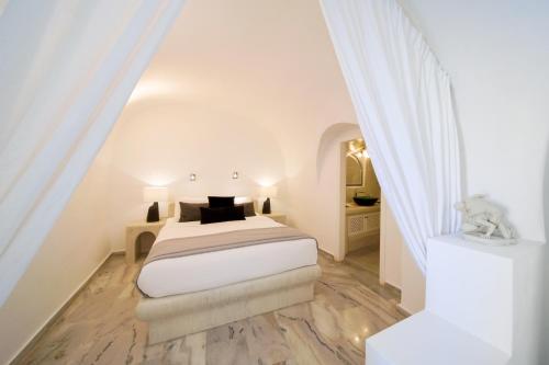 a white bedroom with a bed and a table at Pegasus Villas in Imerovigli