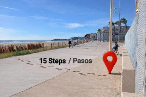 a red marker on a sidewalk next to the beach at La Pineda Pisito Playero in La Pineda