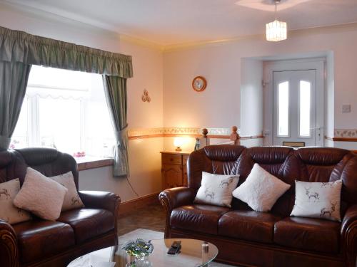 a living room with two leather couches and a table at West Tannacrieff in Stewarton