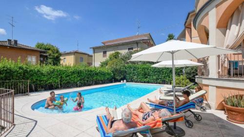 a group of people laying in chairs in a swimming pool at Villa Bugatti Indipendent Villa ,lake view and private pool, DesenzanoLoft Official Partner Homes & Villas by Marriott Bonvoy in Desenzano del Garda