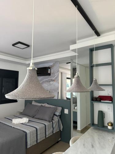 a bedroom with three pendant lights above a bed at Ap Studio Premium luxuoso novíssimo! in Sorocaba