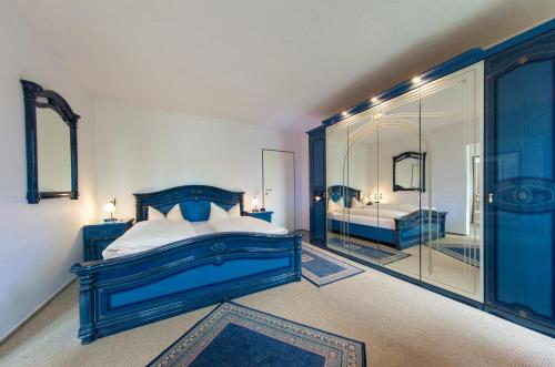 ein blaues Schlafzimmer mit einem Bett und einem Spiegel in der Unterkunft Garni-Hotel An der Weide in Berlin