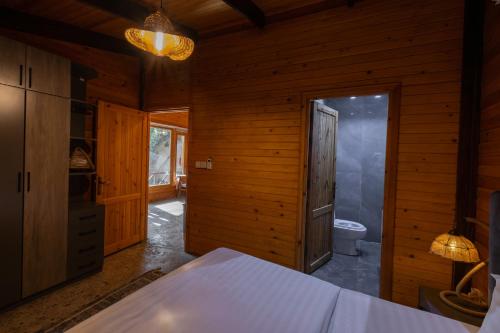 a wooden room with a bed and a toilet at اكواخ لوسو الريفيه in Ḩayy al Ḩamdānīyah