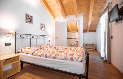 a bedroom with a bed and a desk and a television at Garnì dal Mozat in Ledro