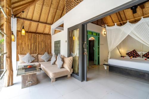 a bedroom in a villa with a bed and a couch at Breathe Villa Meno in Gili Meno
