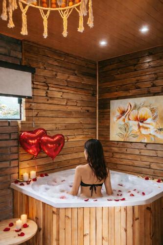 a woman sitting in a bath tub with candles at Chalés Manacá dos Canyons in Praia Grande