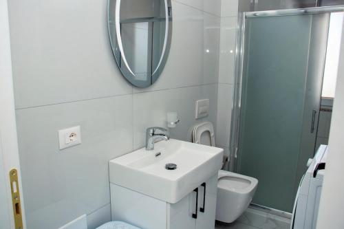 a bathroom with a sink and a mirror and a toilet at Flat in Shëngjin Beachfront Getaway in Shëngjin