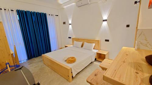 a bedroom with a large bed and blue curtains at Cozy place in Ahangama
