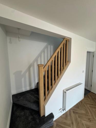 a staircase in a room with white walls and wooden floors at 18 Morawel in Burry Port