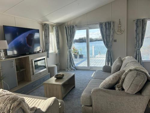 a living room with a couch and a tv at Luxury Lakeview Lodge Chichester Lakeside Holiday Park in Chichester