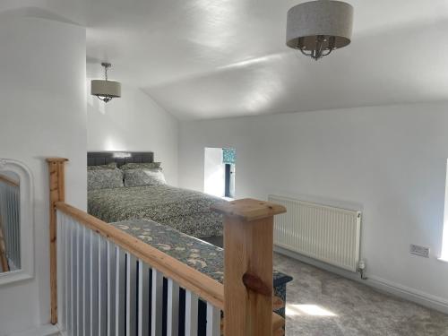 a bedroom with a bed and a wooden staircase at Ty capel cottage in Mold