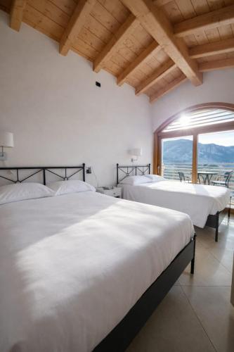 two beds in a room with a large window at Villa Primula in Bellagio