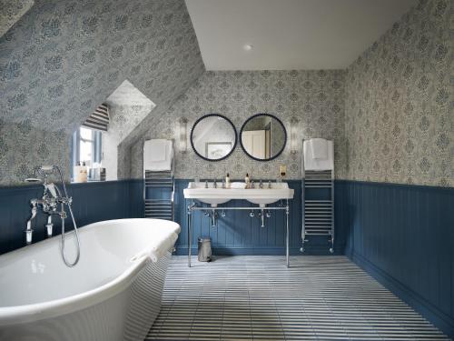 a bathroom with a tub and a sink and mirrors at The Old Bell Hotel in Malmesbury