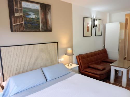 a bedroom with a bed and a chair at Alojamientos Monteverde in Ojén