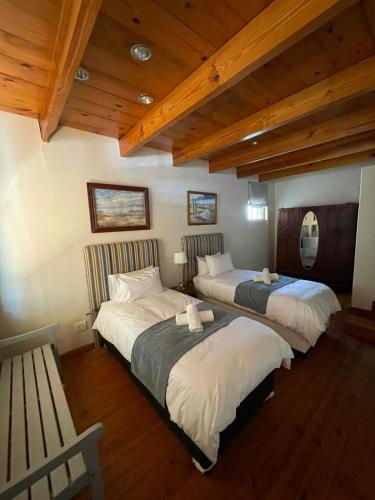 two beds in a room with wooden ceilings at Die Nagmaalhuisie in Montagu