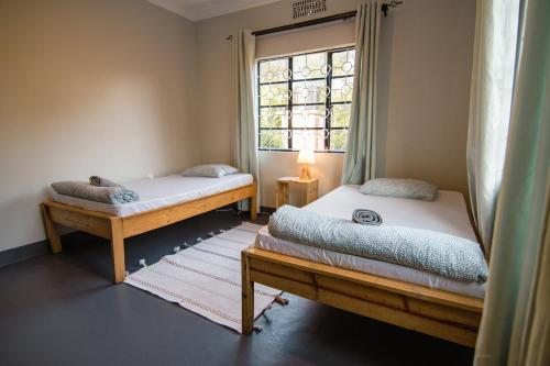 two beds in a room with a window at Open Gate House in Arusha