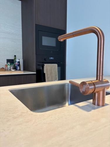 a stainless steel kitchen sink with a faucet at Pirate, op 100 meter van strand in Koksijde